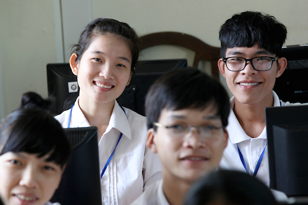 PNV students in the classroom working on computer looking up at the camera.