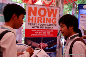 2 students discussion in front of a company booth